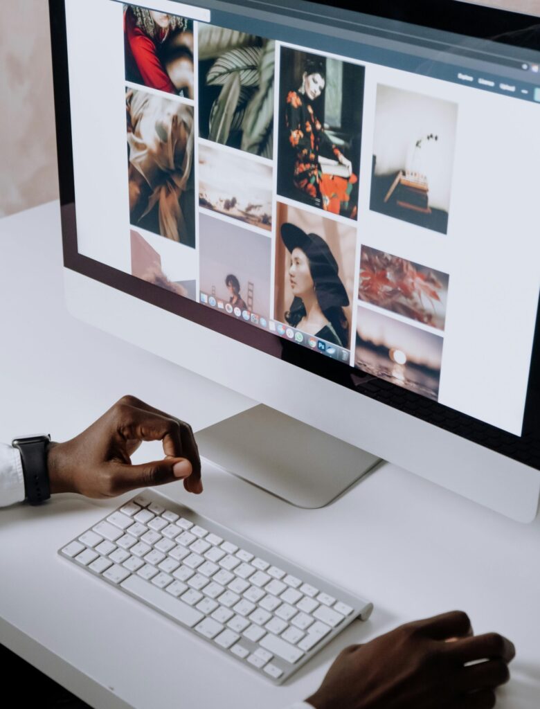 Man working on computer in modern office, viewing photography website. Clean and tech-focused environment.